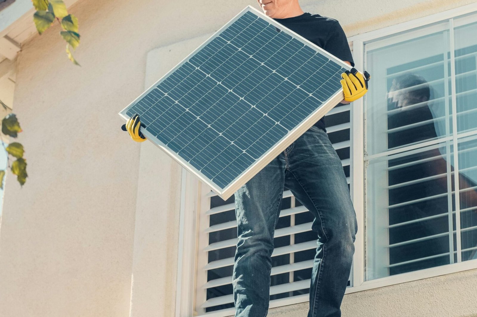 A technician is installing a solar panel on a house roof, promoting clean energy solutions.